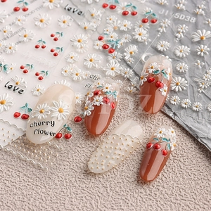 Macro detail of 5D embossed nail art stickers with cherry and daisy floral patterns