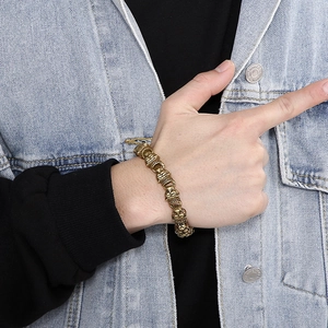 Detail of a bold gold stainless steel bracelet with vintage embossed patterns on wrist