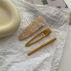 Close-up of three-piece hair clip set with marble texture and mustard yellow resin