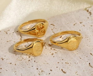 Vista dettagliata di tre anelli sigillo placcati oro 18K con motivi floreali su pietra