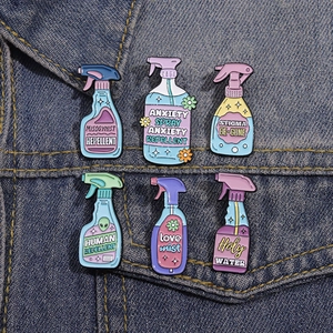 Set of 6 colorful spray bottle enamel pins with slogans on blue denim jacket