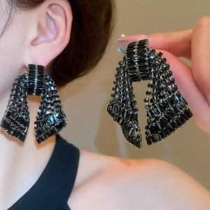 Detailed close-up of layered black crystal fringe earrings with sparkling geometric beads