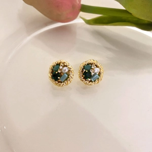 Macro detail of vintage round stud earrings with crystals and pearls on white porcelain