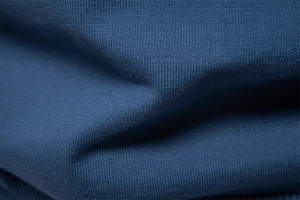 Macro view of navy blue V-neck sweater fabric showing fine knit texture and soft material