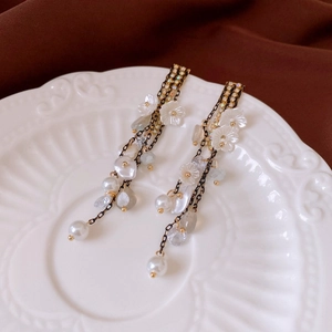Detail of vintage gold tassel earrings with white flowers and pearls on ceramic plate