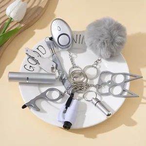Detail of gray self-defense keychain set with alarm and spray bottle on a white plate