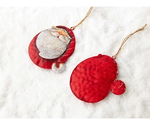 Detail of vintage metal Santa and red glove ornaments with jute rope on white snow