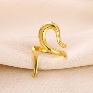 Macro di un anello a serpente placcato oro su tessuto di seta beige con linee sinuose