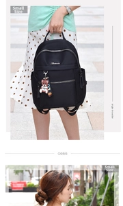 Detail of small black Oxford nylon backpack featuring a bear charm and silver zippers