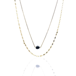 Detail of layered gold necklace with black irregular stone pendant and paperclip chain