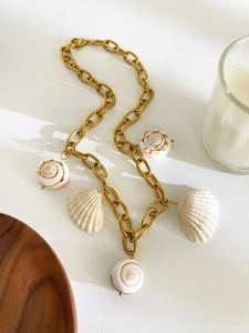 Close-up of golden chunky chain necklace with natural seashell and conch pendants