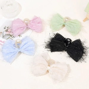 Flat lay of colorful plush bow hair clips with silk fringe in five soft pastel shades