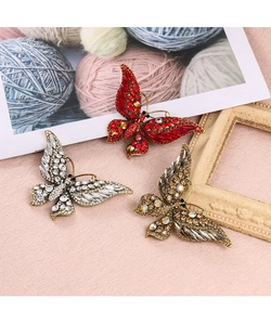 Vue détaillée de trois broches papillon avec strass sur un fond décoratif en laine