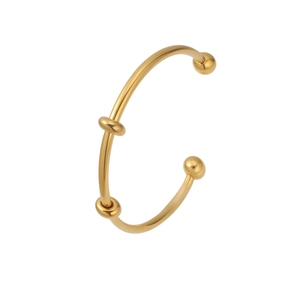 Detailed view of golden open cuff bracelet with polished finish and bead accents