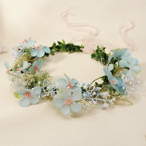 Close-up of a floral headband with blue flowers, green leaves and a pink ribbon