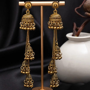 Vintage Jhumka drop earrings with gold tassels and engraved flower details on black velvet