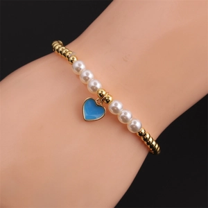 Detail of beaded bracelet with gold copper beads, white pearls and blue heart charm