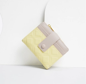 Detail of yellow and purple patchwork short wallet with quilted pattern and snap button