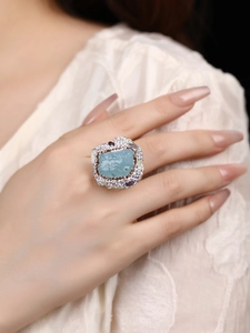 Detailed close-up of a large open ring with raw aquamarine stone and colorful zircon pavé