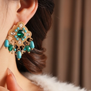 Gros plan détaillé de boucles d'oreilles vintage en or avec pierres vertes sur un mannequin