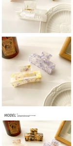 Detail showing various acetate hair claws with floral and marble patterns in a lifestyle set