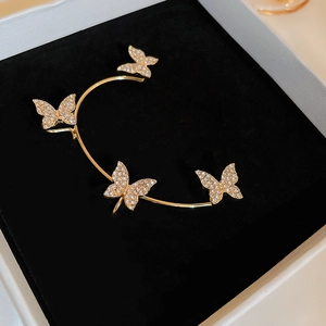 Detailed close-up of gold butterfly ear cuff with sparkling rhinestones on black velvet