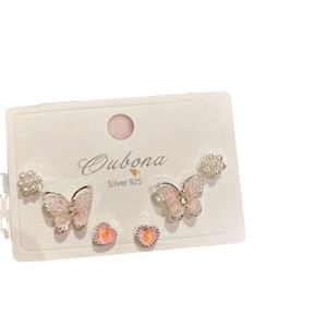 Three pairs of sweet silver stud earrings with butterfly, pearl, and heart designs on white card