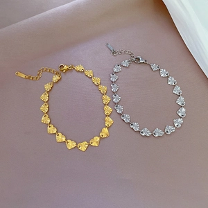 Detail of heart chain bracelet featuring radial texture in gold and silver steel finish