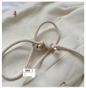 Detail of woven straw bag fabric featuring cream texture and gold drawstring tips