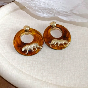 Close-up of leopard pattern tassel earrings with amber resin and golden cheetah detail