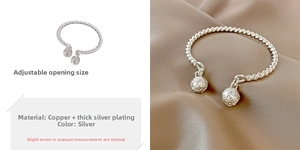 Detalle de brazalete trenzado plateado con abertura ajustable y esferas grabadas