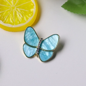 Close-up of sky blue butterfly brooch with gold alloy base and marble resin wings