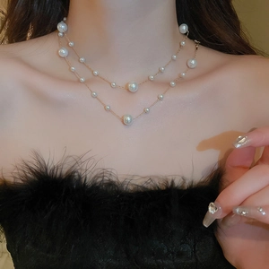 Detail view of double-layered gold plated pearl necklace worn on model's neck