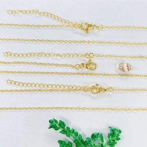 Close-up of gold-plated necklaces featuring lobster clasps and extension chains on a table