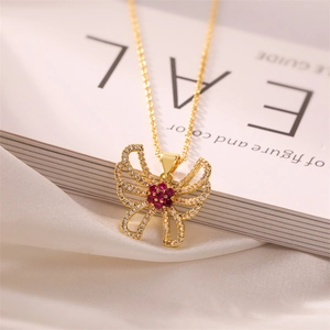 Detail of gold butterfly necklace with red and white crystals on silk background