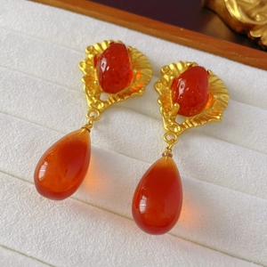 Macro shot of vintage strawberry earrings with amber teardrop pendants on white velvet