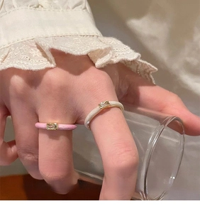 Close-up of gold rings with pink and cream enamel set with rectangular cubic zirconia
