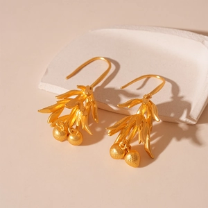 Close-up of vintage matte gold leaf earrings on a minimalist white plaster tray