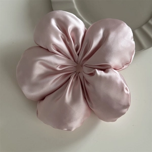 Close-up of pink satin flower hair tie with smooth silk texture on white surface
