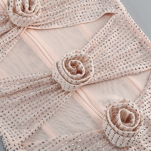 Détail de maille rose avec strass argentés et appliques florales 3D sur la robe