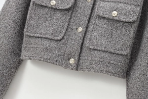 Détail d'une veste en tweed gris montrant des boutons dorés et le tissu