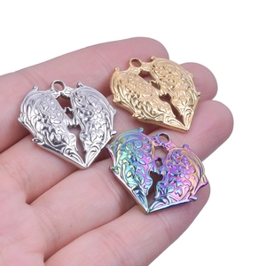 Trois pendentifs cœur en or, argent et arc-en-ciel tenus en main pour voir la taille