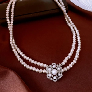 Close-up of double-layer white glass pearl necklace with vintage silver flower clasp