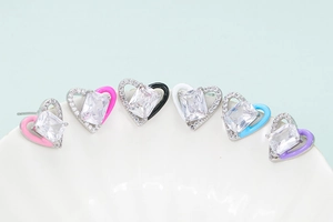 Macro view of multi-color heart earrings with zircon inlay and enamel details on white ceramic