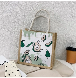 Close-up of canvas lunch bag with cartoon avocado print and woven burlap handles