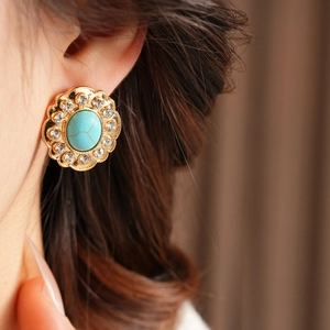 Vue détaillée de la boucle d'oreille fleur dorée avec pierre turquoise et strass