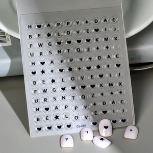Détail de stickers à ongles 3D avec lettres noires et étoiles sur des ongles roses