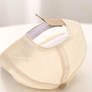 Adjustable Velcro strap detail on the back of a beige breathable baby baseball cap