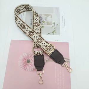 Detail of ethnic embroidery bag strap with gold metal hooks on a magazine background