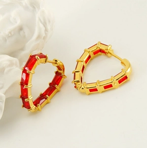 Detail of heart hoop earring with red rectangular stones and gold 18K plating